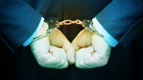 close up on the hands of a main wearing a suit in hand cuffs